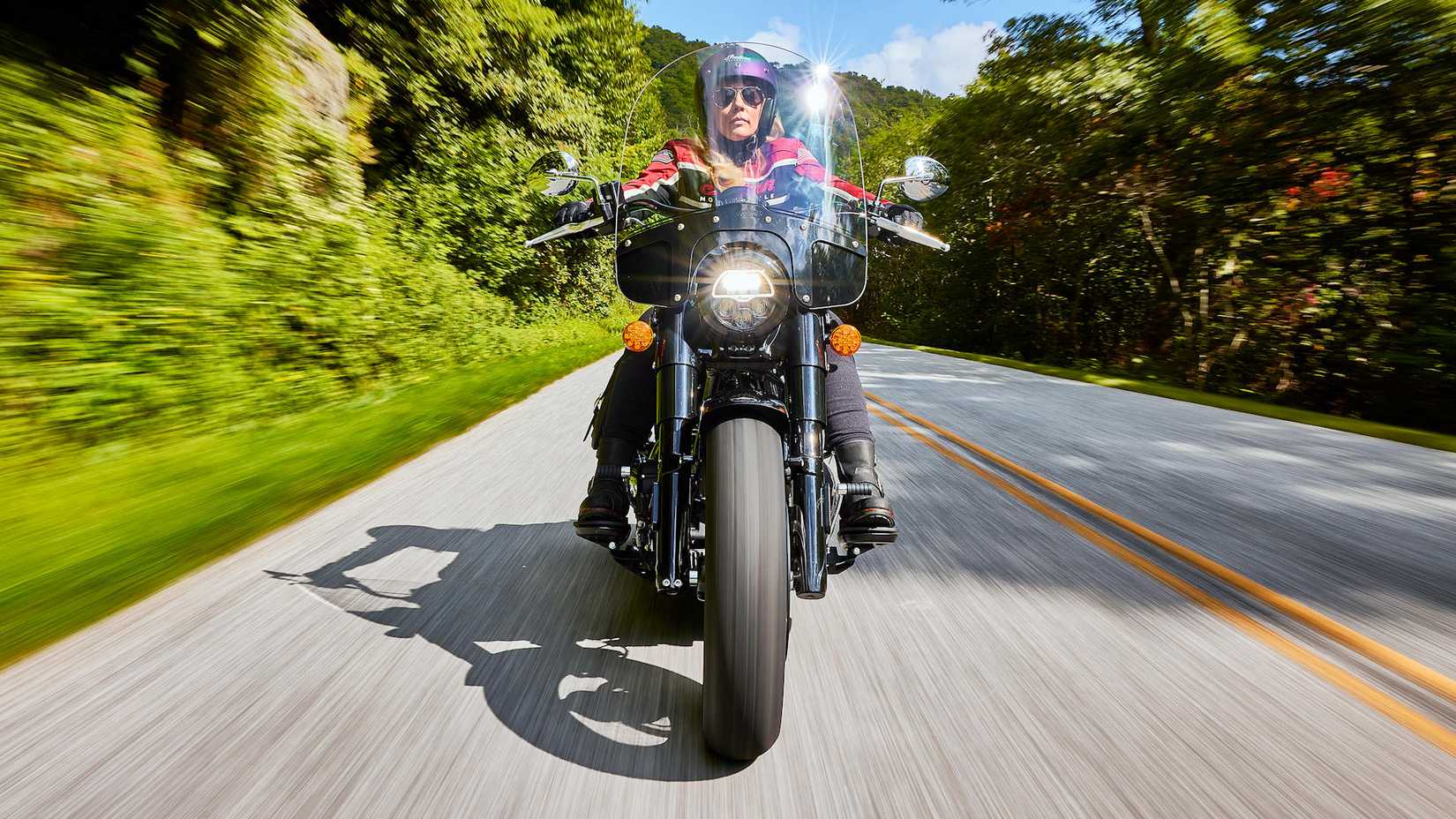 Piloto em um Indian Super Chief 2025 navegando em uma estrada arborizada