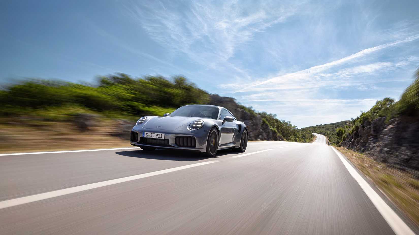 Foto de ação de um Porsche 911 Turbo S 2025 acelerando em uma estrada secundária