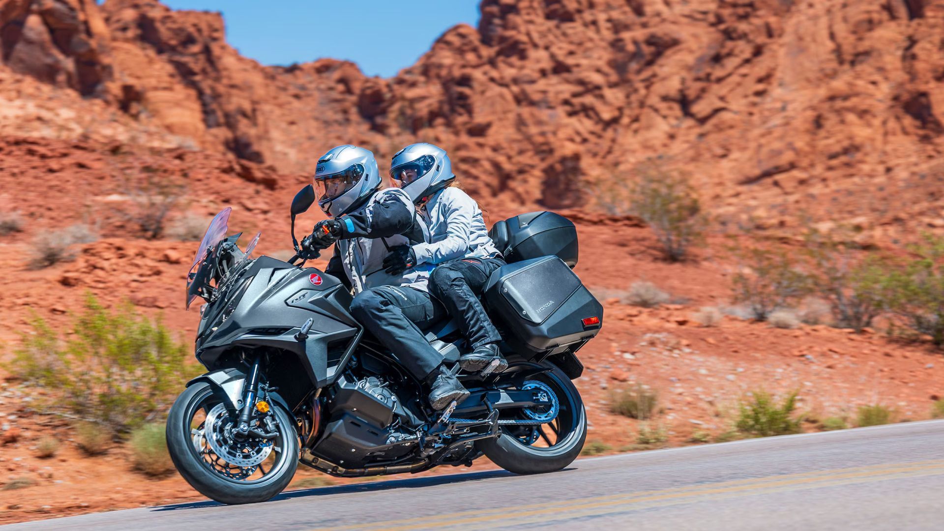 Tracking shot of a 2026 Honda NT1100 DCT being ridden two-up along desert road
