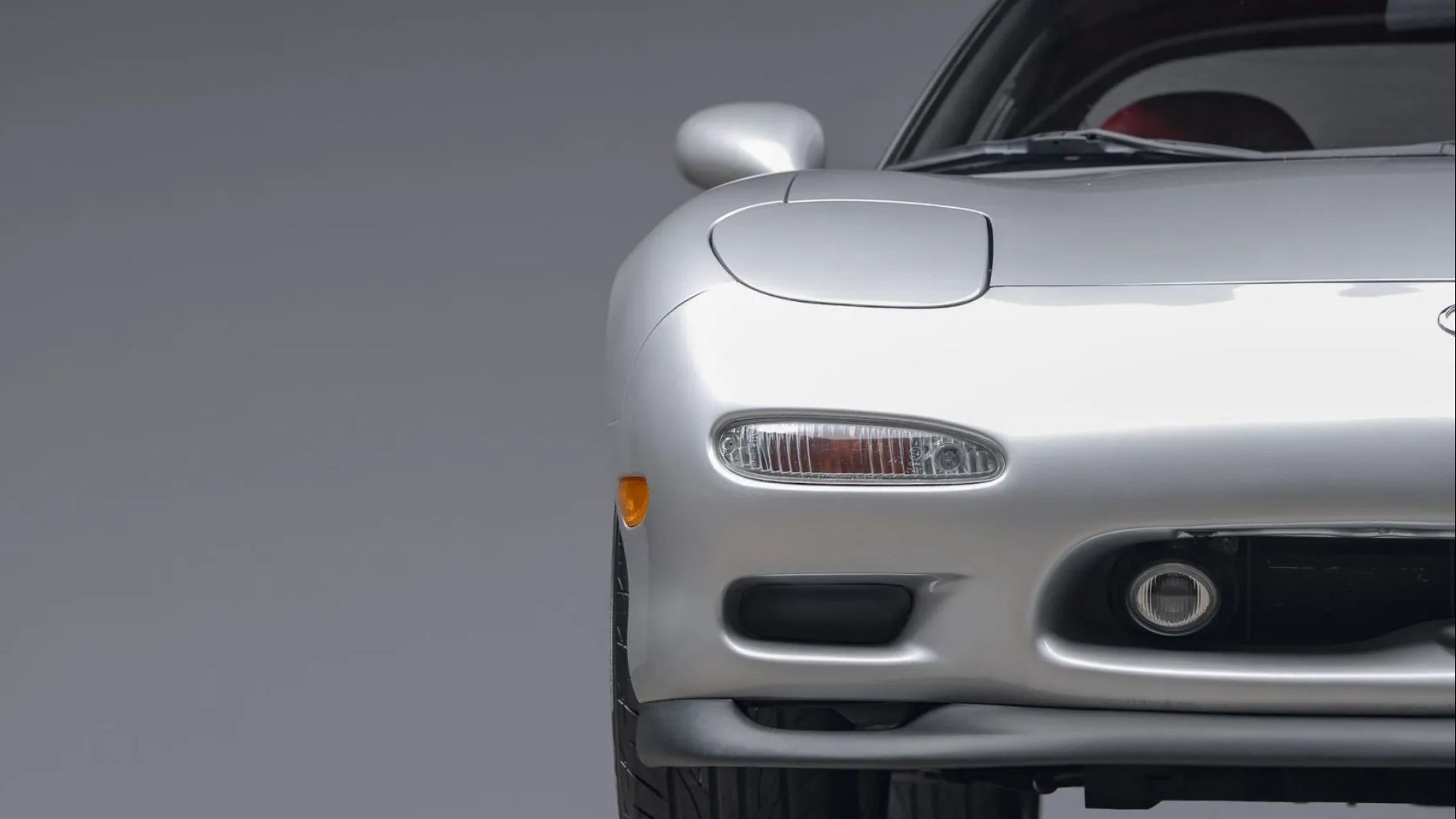 A close-up of the front end of a silver 1993 Mazda RX-7 Touring 5-Speed headlight