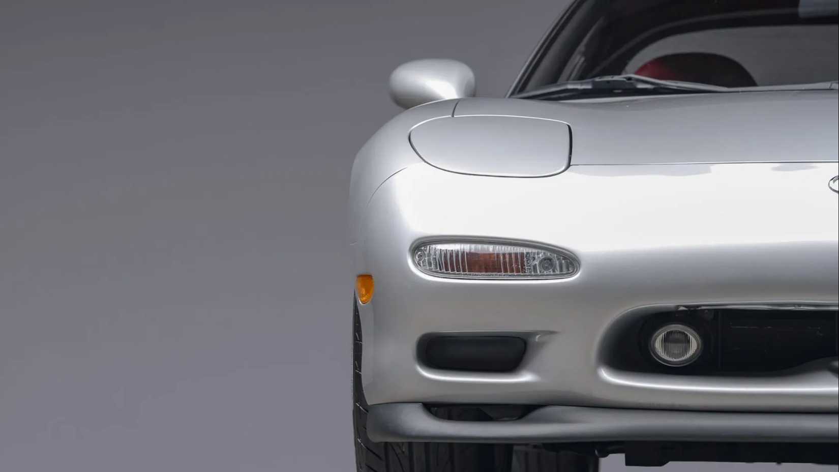 Um close da extremidade dianteira de um farol prateado Mazda RX-7 Touring de 5 velocidades 1993