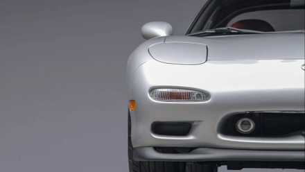 A close-up of the front end of a silver 1993 Mazda RX-7 Touring 5-Speed headlight