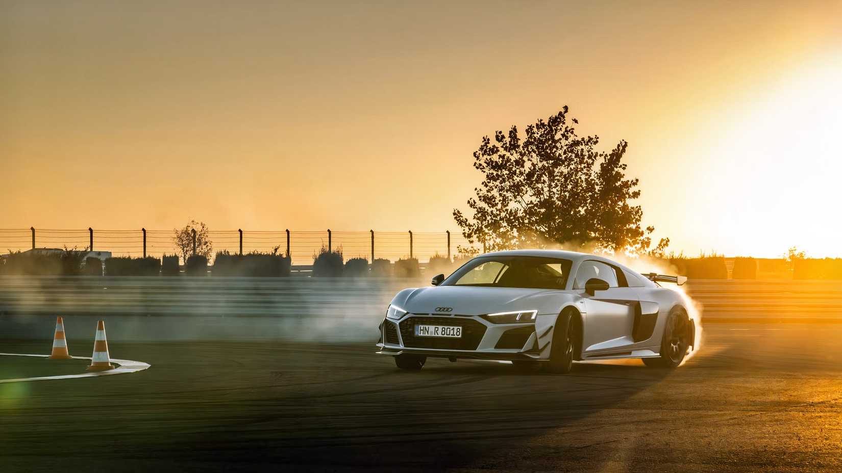 Audi R8 GT cinza 2023 à deriva em uma pista ao pôr do sol