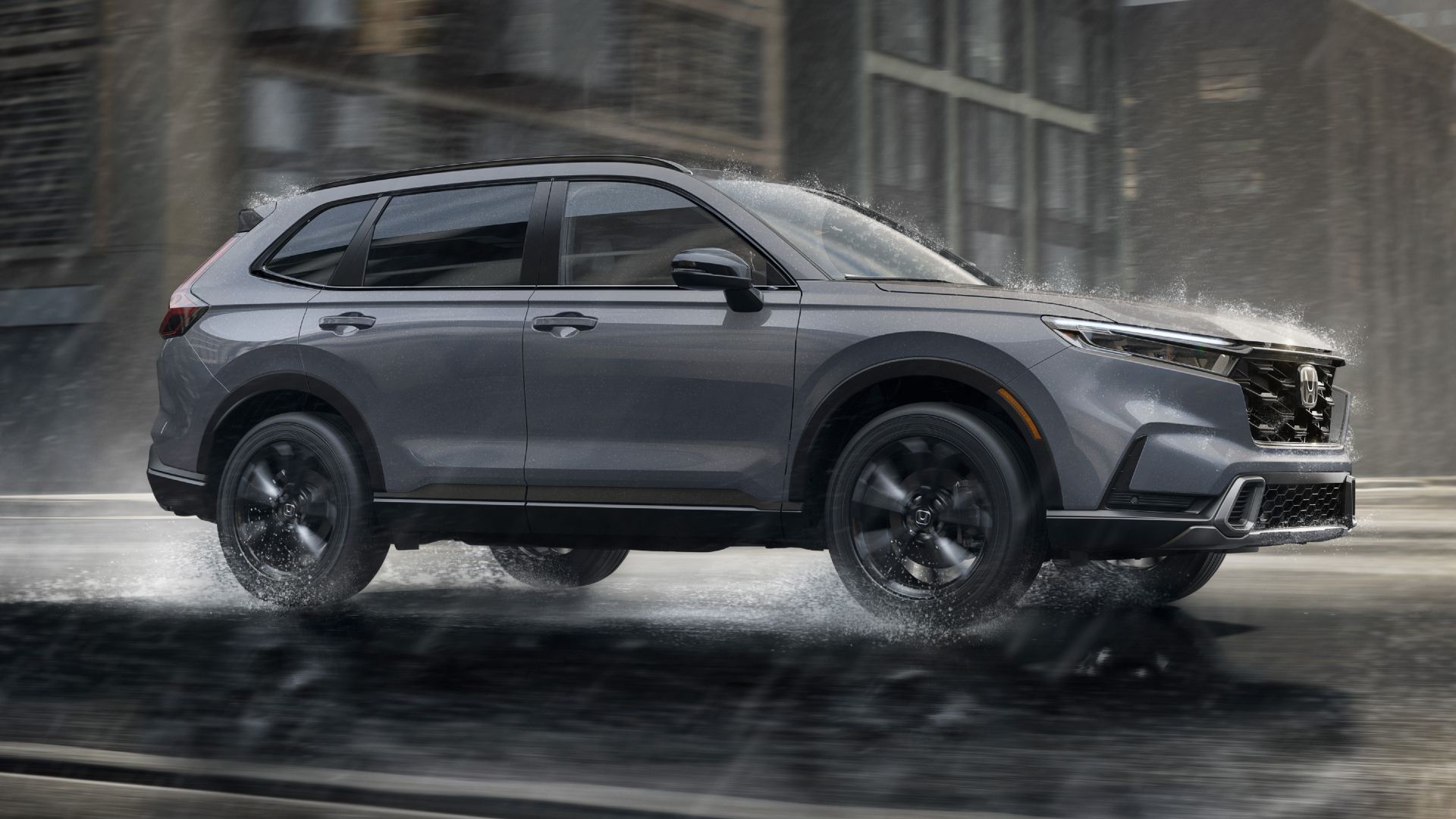 Foto de perfil lateral de um Honda CR-V Sport Touring Hybrid cinza 2026 dirigindo na chuva. 