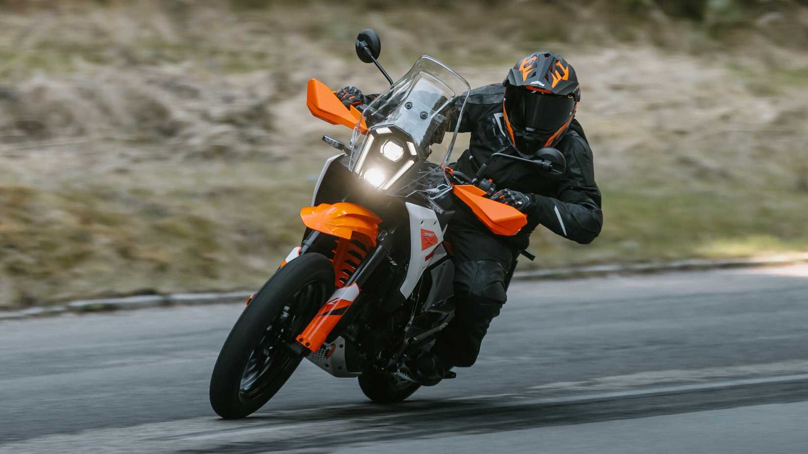 2026 KTM 390 Adventure X fazendo curvas rápidas na frente do asfalto, cena cinematográfica do terceiro quarto