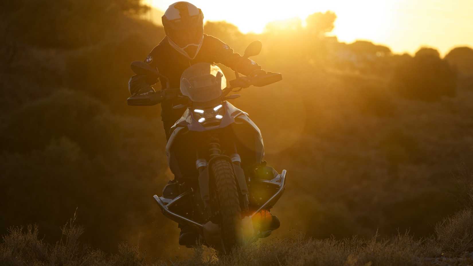 Foto cinematográfica do painel frontal da BMW R 1300 GS 2026 andando longe do pôr do sol