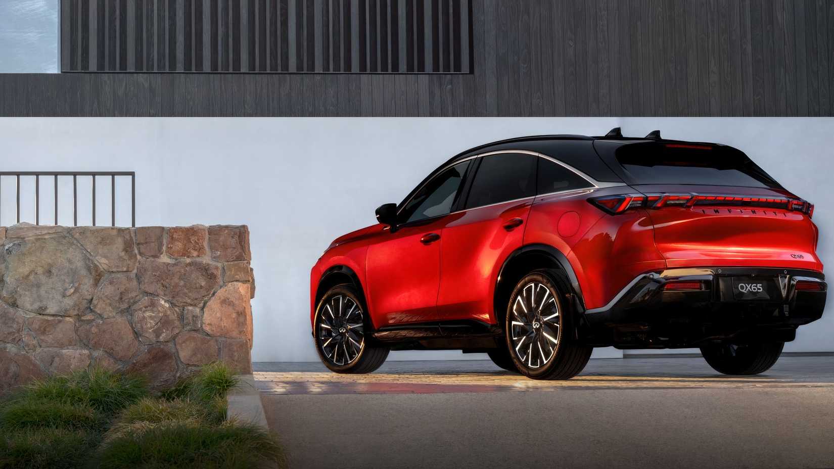 Foto traseira 3/4 de um Infiniti QX65 2027 vermelho estacionado em frente à casa