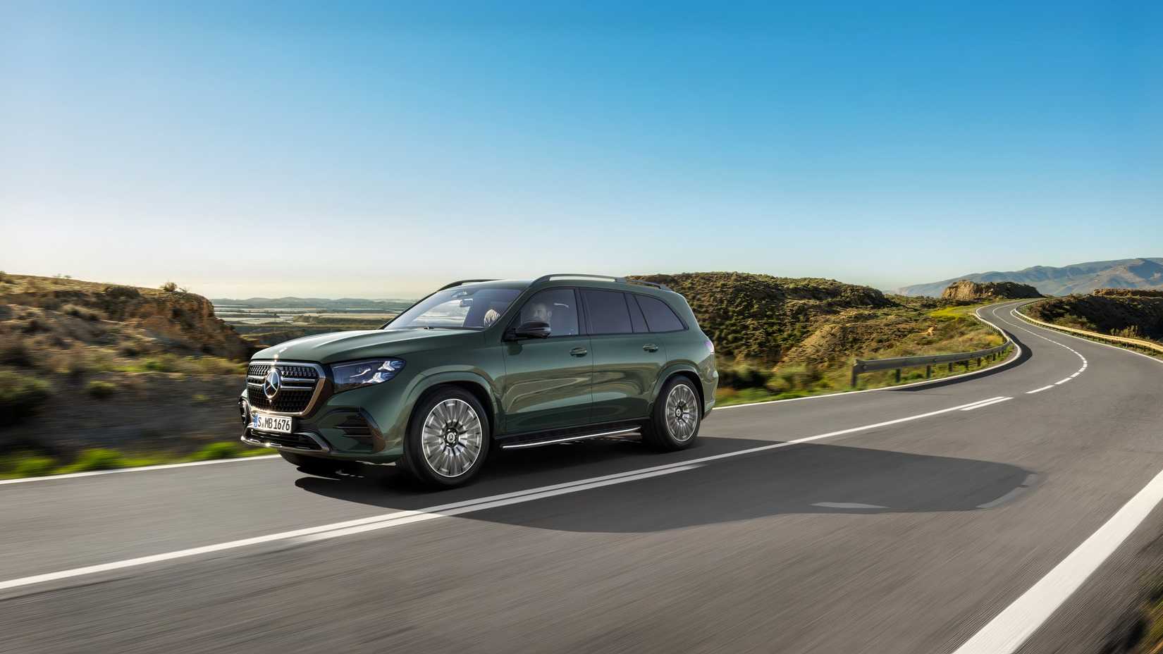 Front 3/4 shot of a green 2027 Mercedes-Benz GLS driving down mointain road