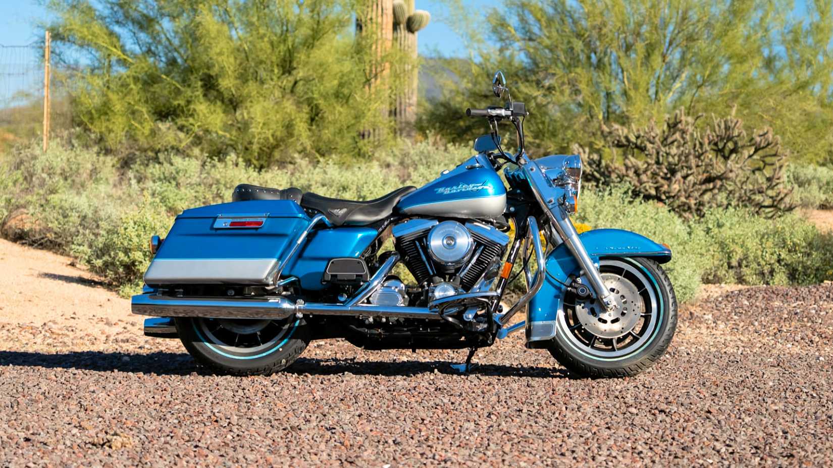 Foto de perfil estático da Harley-Davidson Road King de 1994 estacionada em uma estrada de cascalho