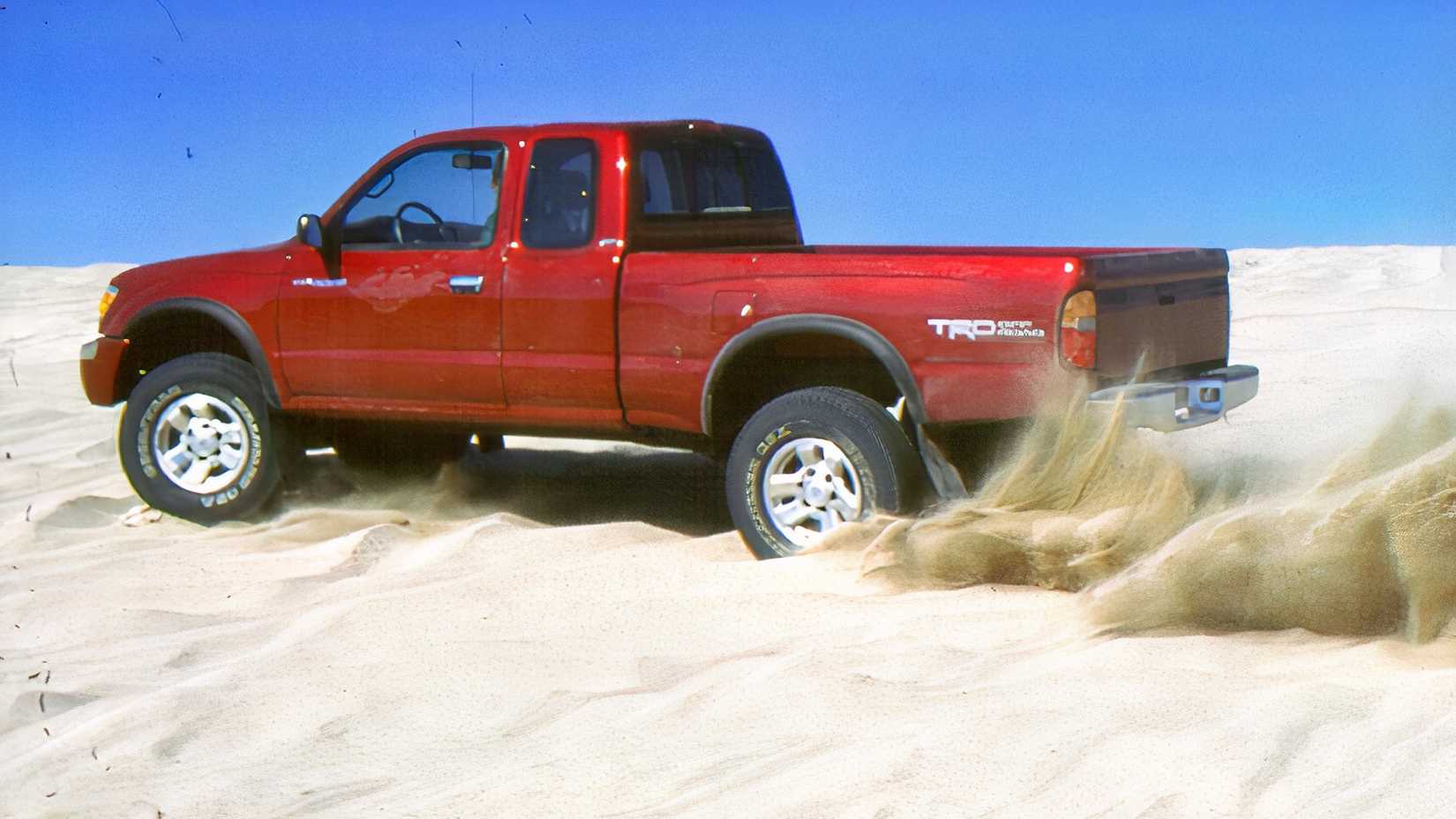 Side shot of a red 1998 Toyota Tacoma burnout in sand