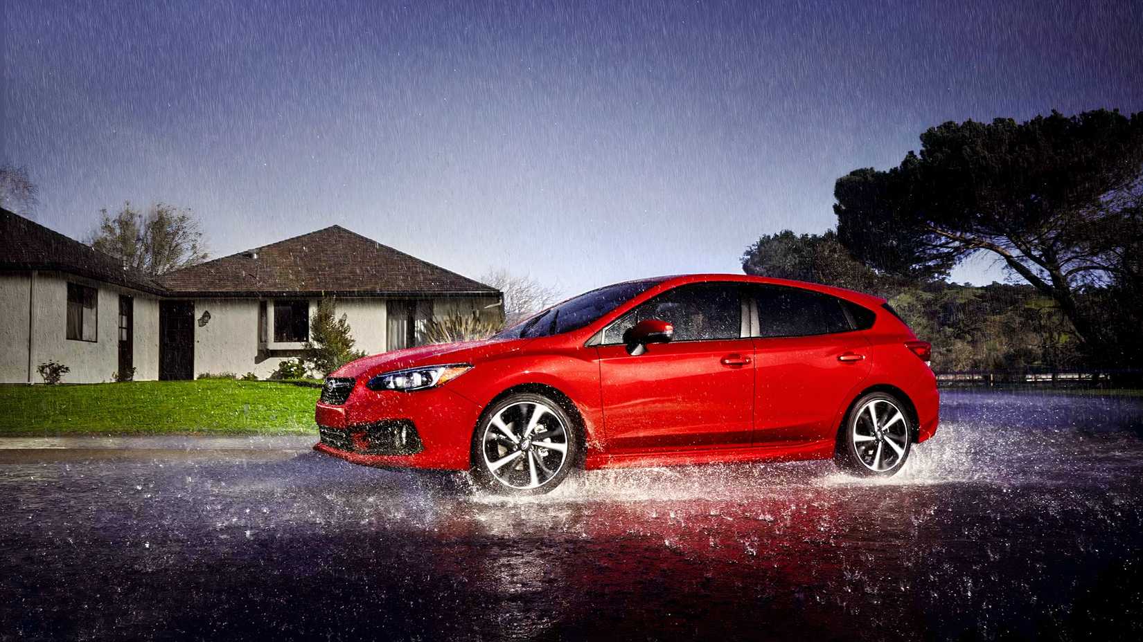 Foto lateral de um Subaru Impreza Hatchback 2023 vermelho dirigindo na chuva