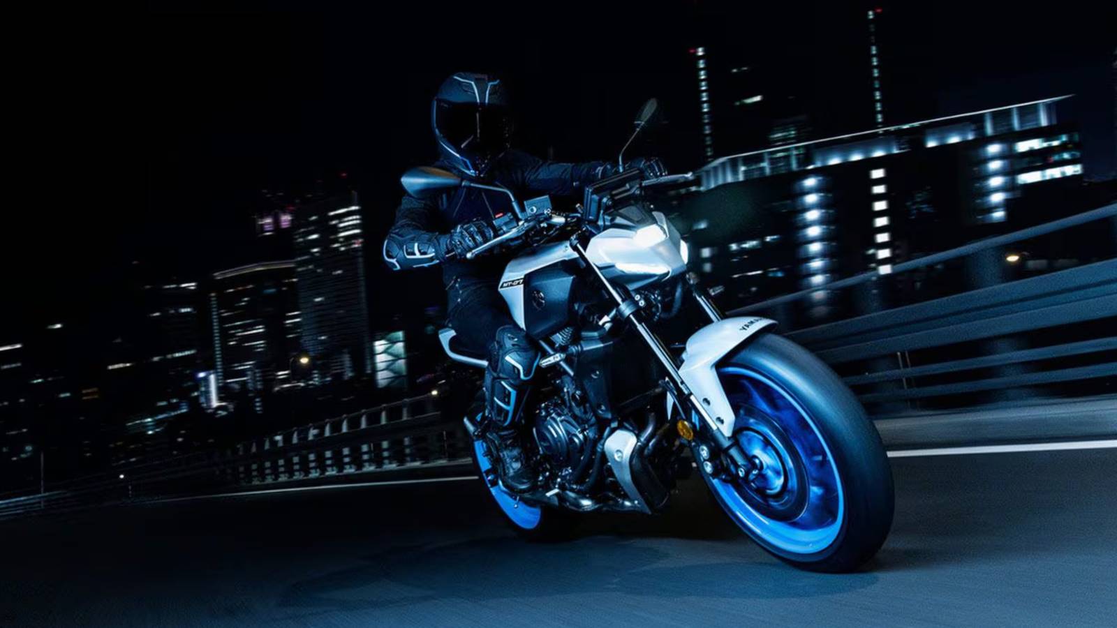 Una Yamaha MT-07 in movimento su un ponte in città di notte, con luce di fondo