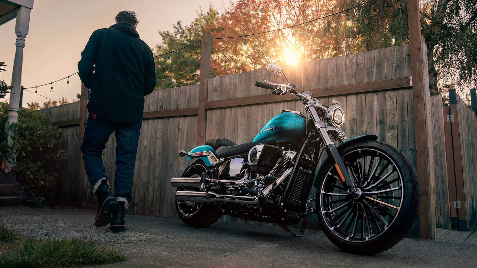 Uma Harley-Davidson Breakout estacionada com o piloto caminhando até ela