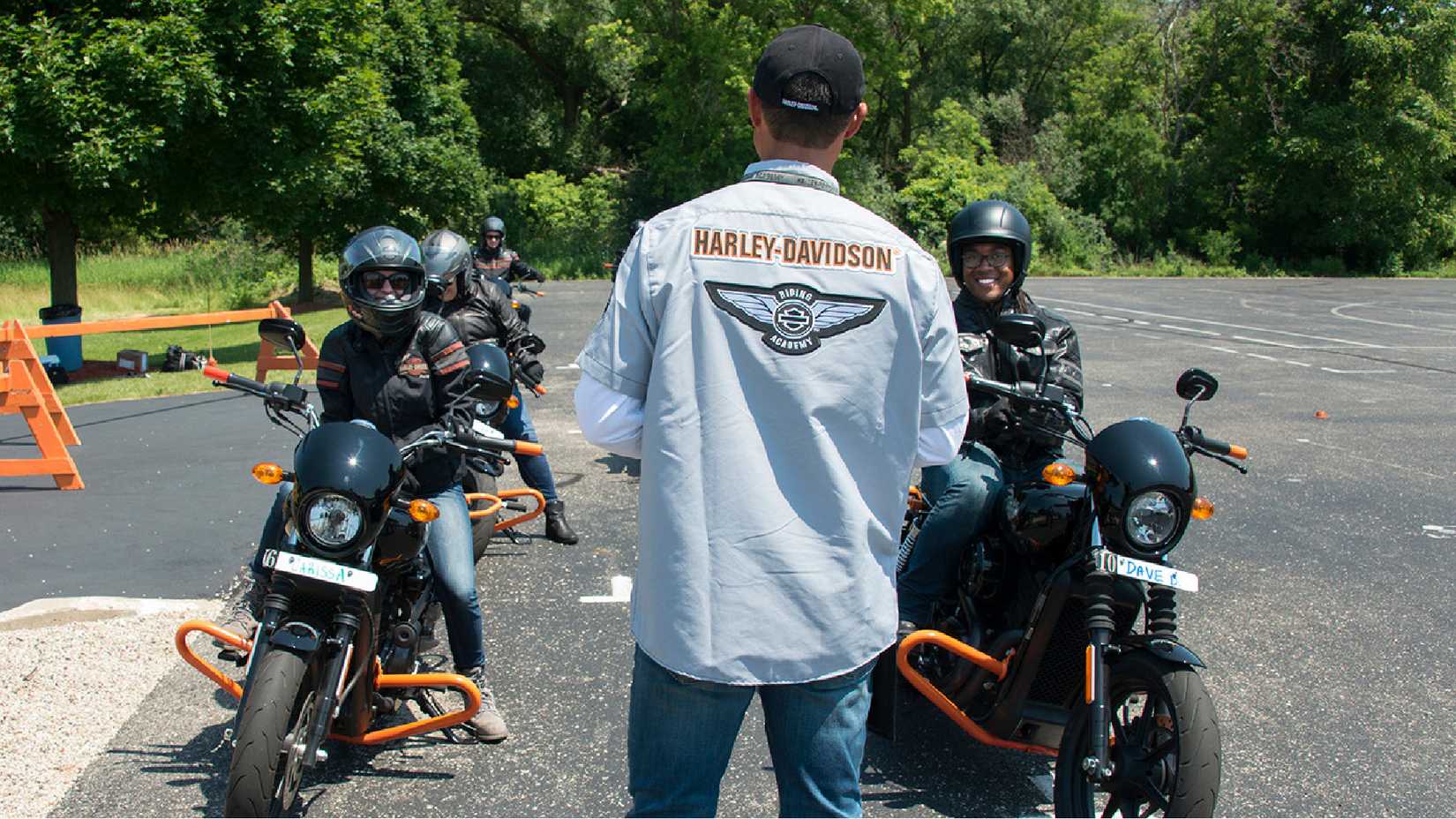 A Harley Davidson beginner riding course instructor speaks to riders on their bikes