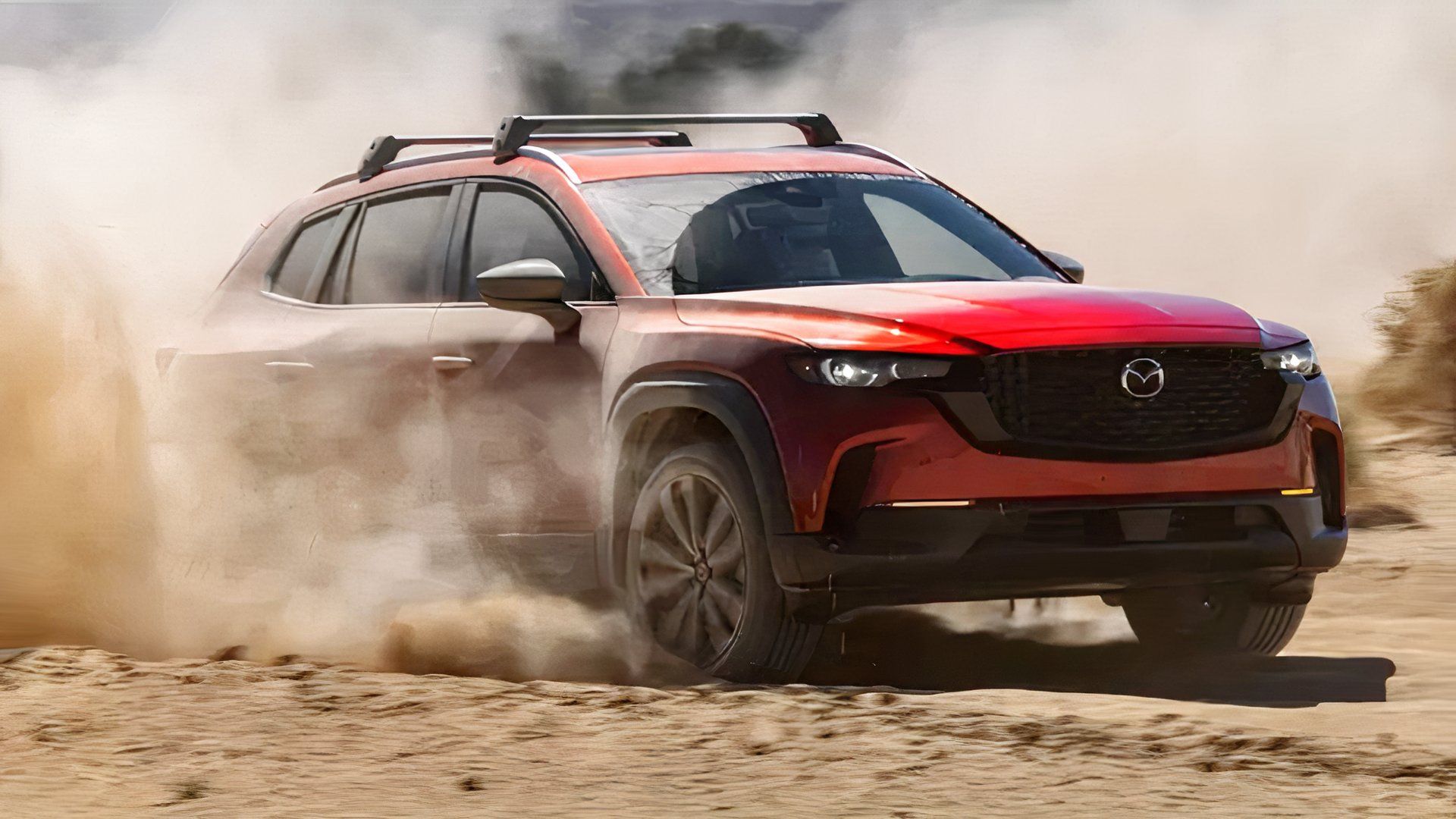 Foto frontal de um Mazda CX-50 2026 vermelho levantando poeira fora da estrada
