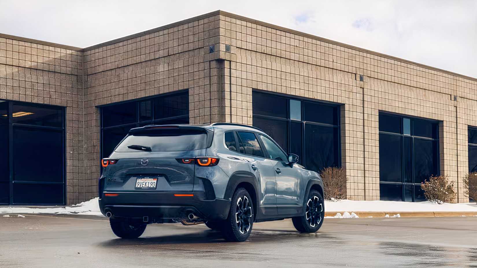 Rear 3/4 shot of a gray 2026 Mazda CX-50 parked in front of building