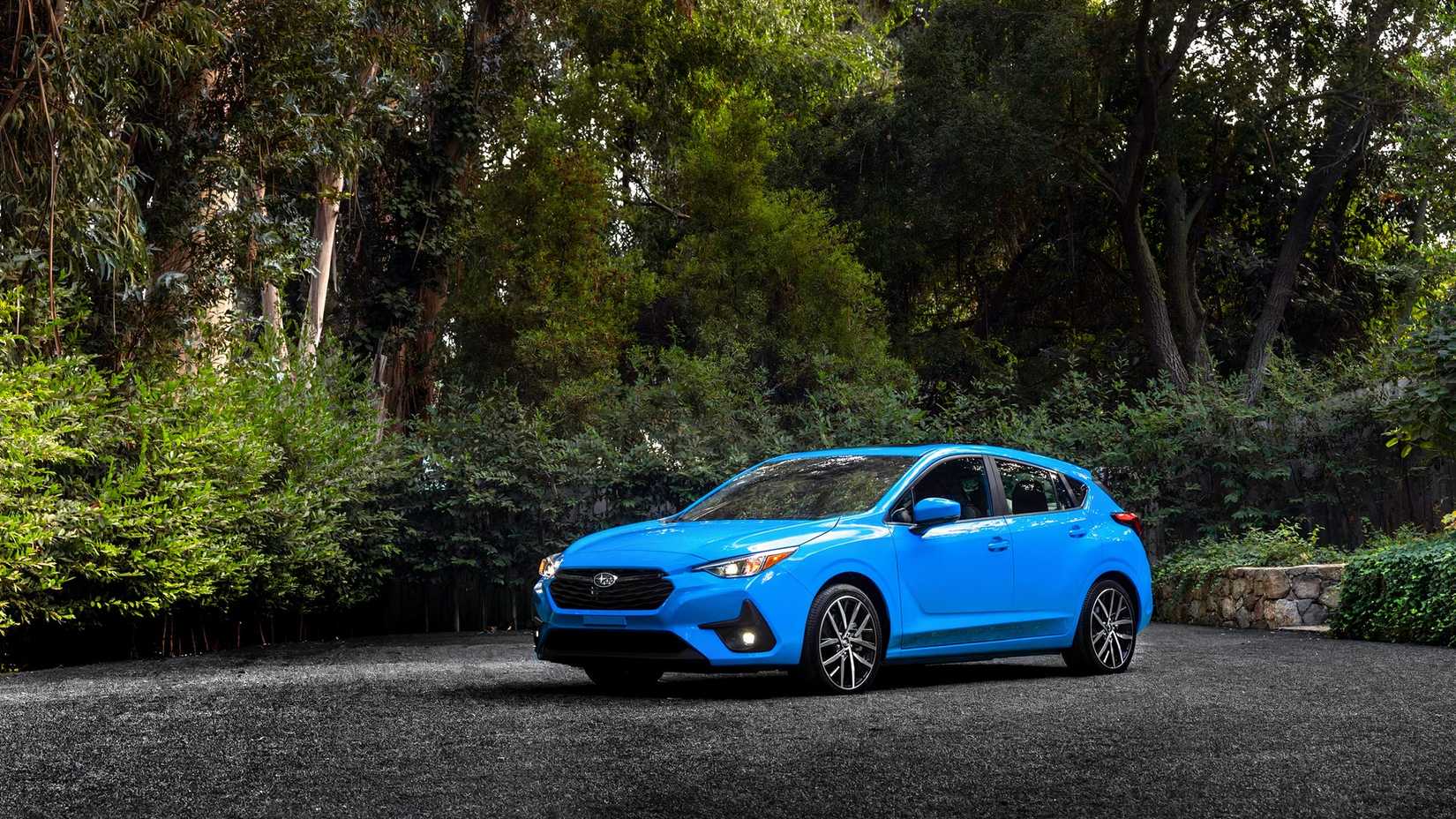 Front 3/4 shot of a blue 2026 Subaru Impreza Hatchback parked in dirt