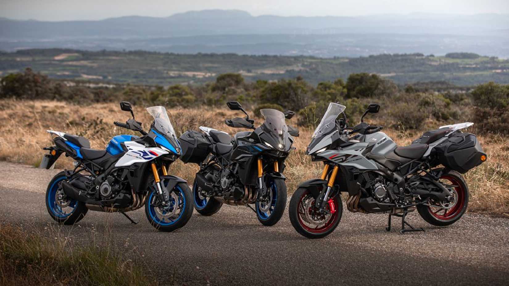 Imagem estática de três motos Suzuki GSX-S1000GX+ estacionadas uma ao lado da outra