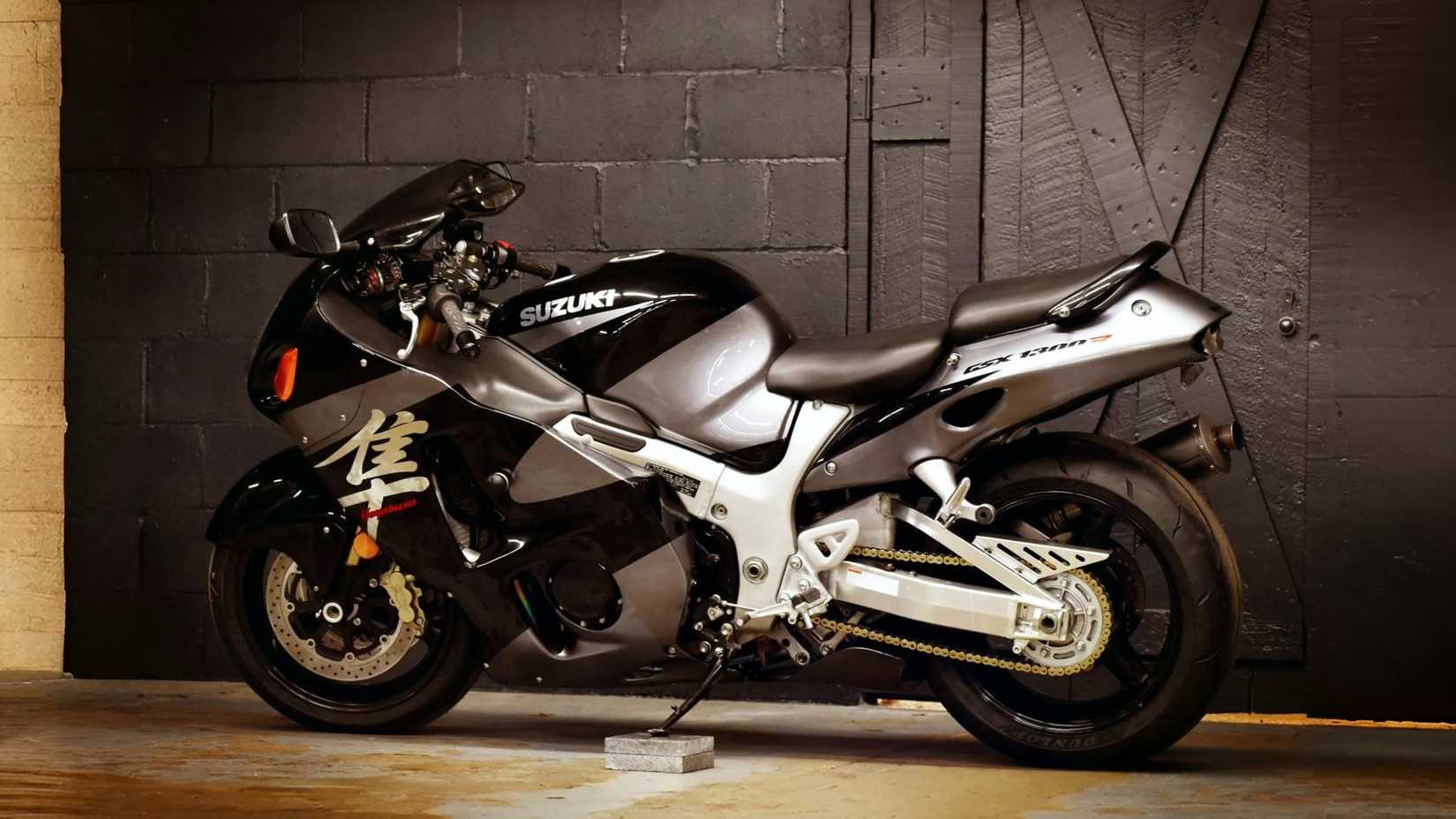 A black 2004 Suzuki Hayabusa parked in a barn, side profile view