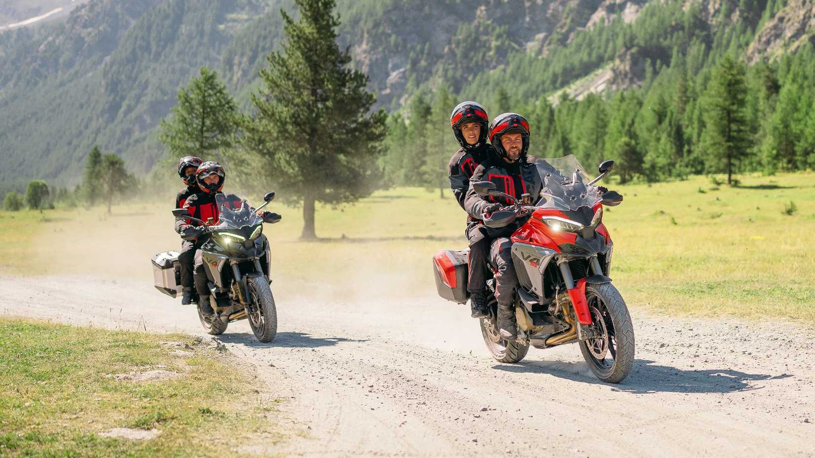 Two Ducati Multistrada V4s riding two-up on dirt trail