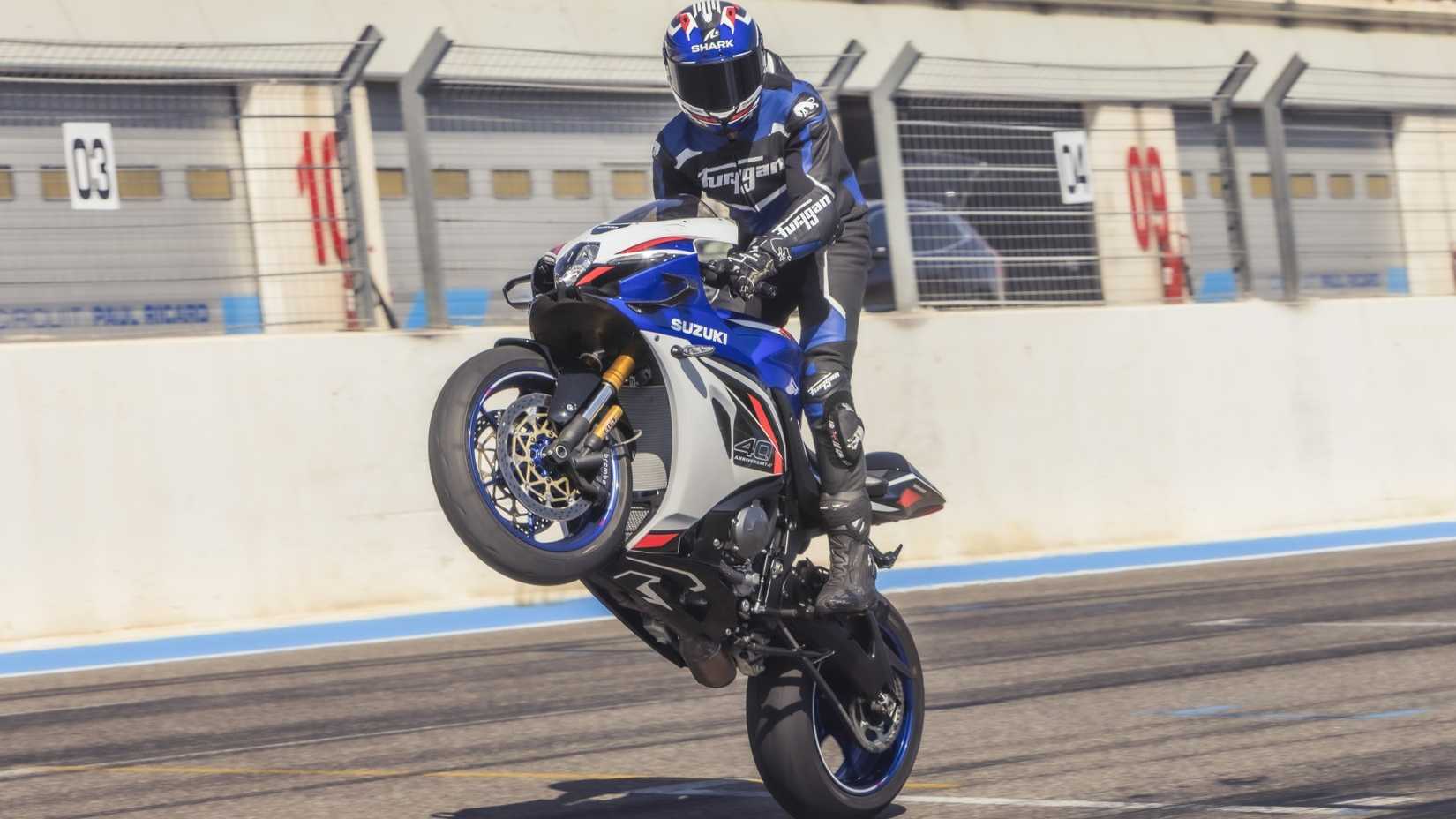 2026 Suzuki GSX-R1000 dando um cavalinho na pista de corrida, vista frontal do terceiro quarto