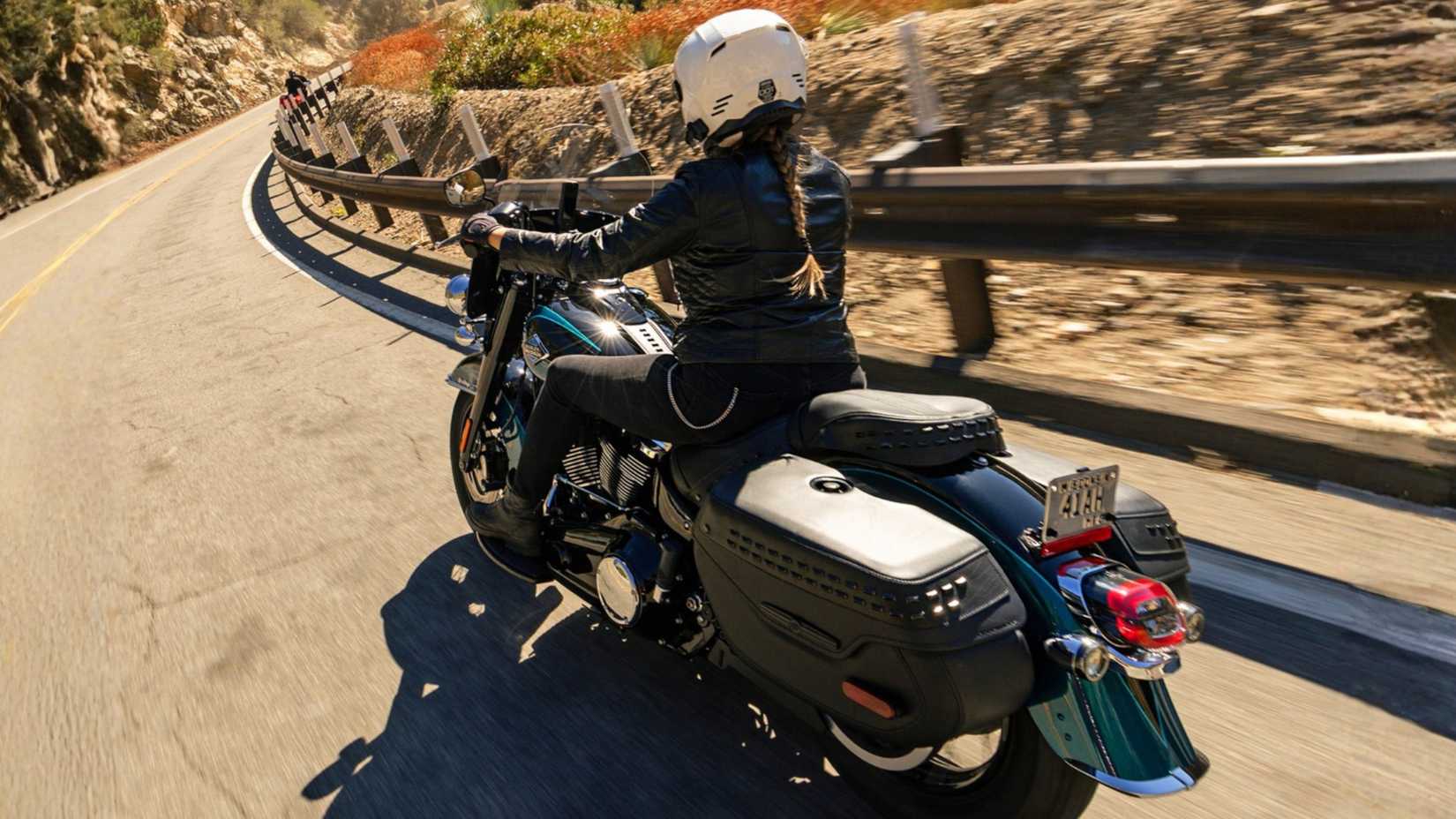 Pilote uma Harley-Davidson Heritage Classic 2026 azul entrando em uma curva
