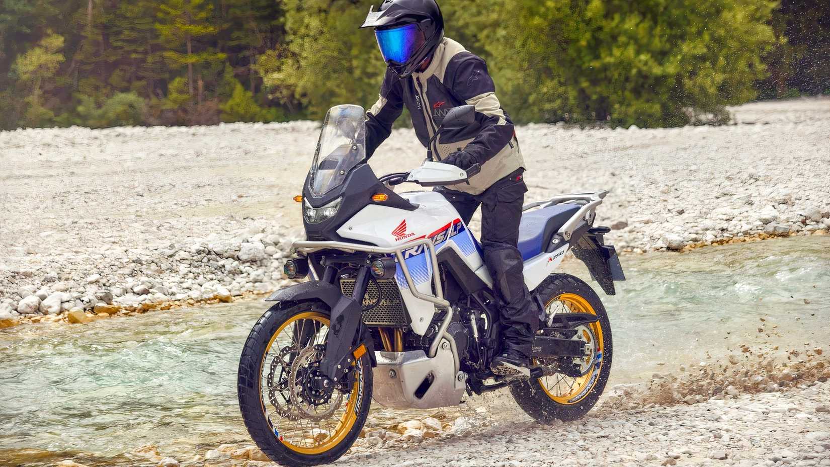 Honda XL750 Transalp andando em uma trilha perto de um riacho