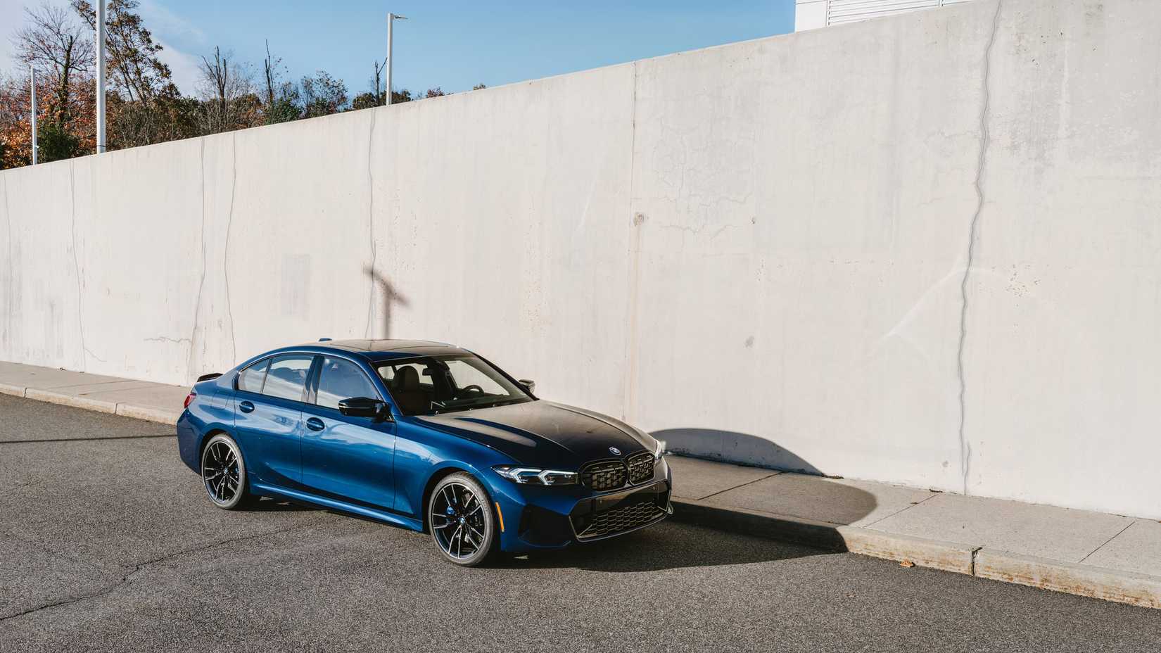 Foto frontal 3/4 do BMW M340i 2026 estacionado próximo à parede
