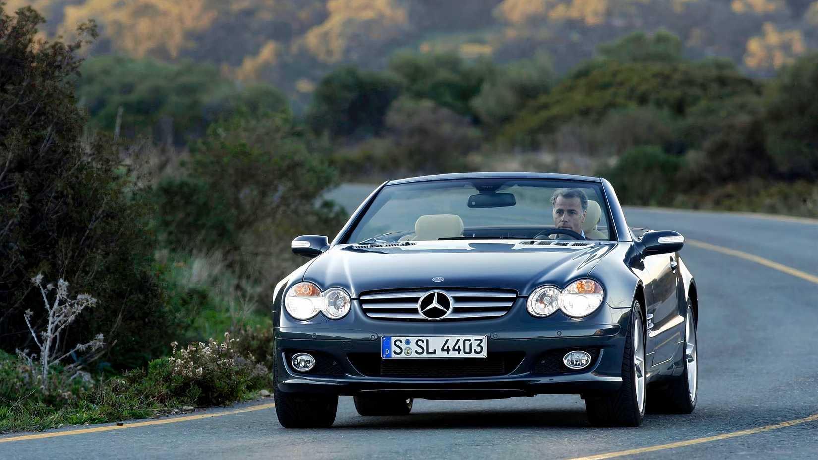 A R230 Mercedes-Benz SL driving down a twisty road