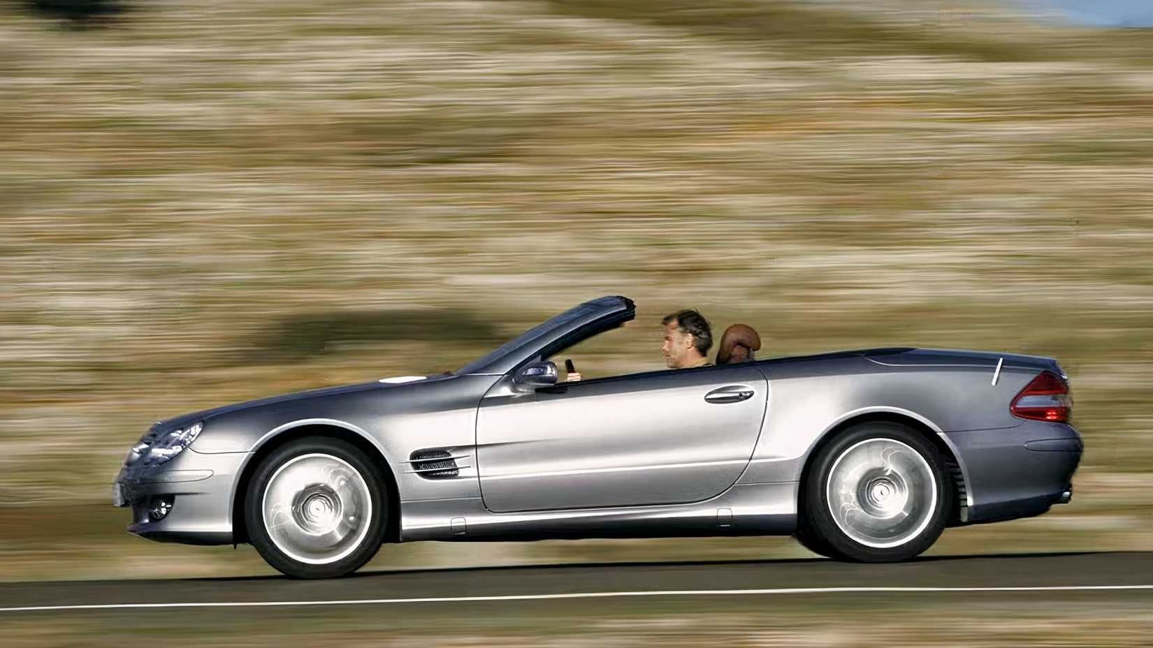 A R230 Mercedes-Benz SL from the side driving down a country road