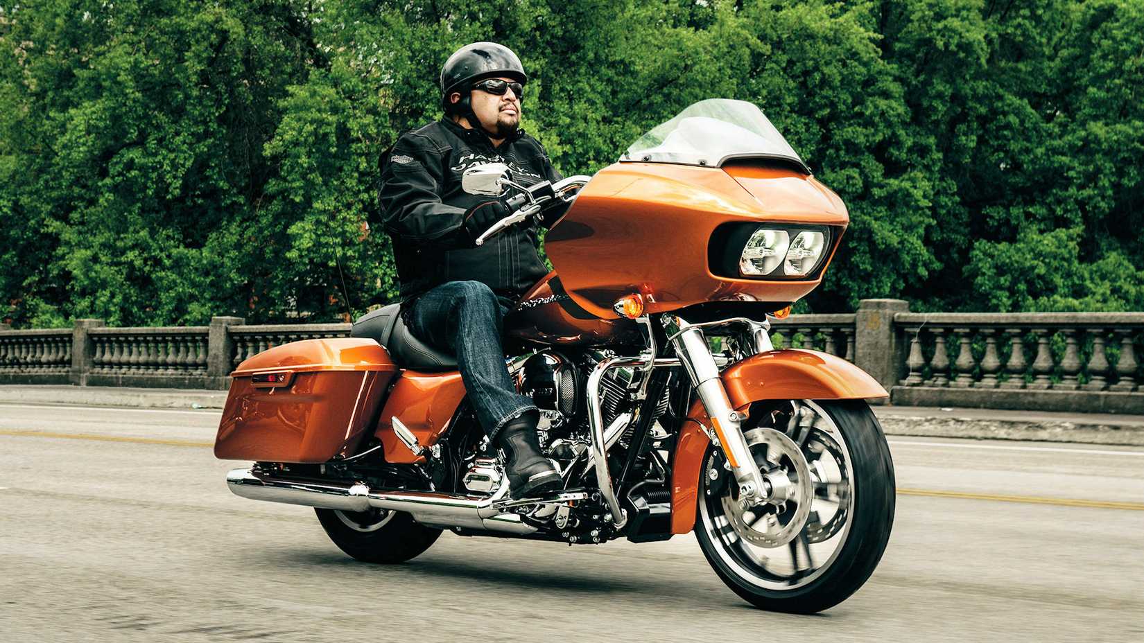 Rider on an orange 2015 Harley-Davidson Road Glide cruising over a bridge