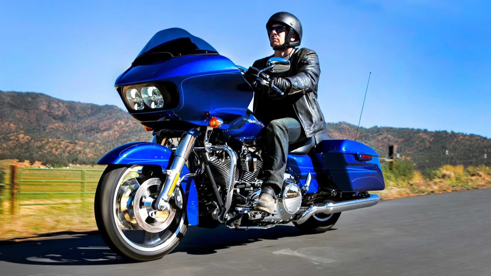 Piloto em uma Harley-Davidson Road Glide azul 2015 navegando em uma estrada secundária