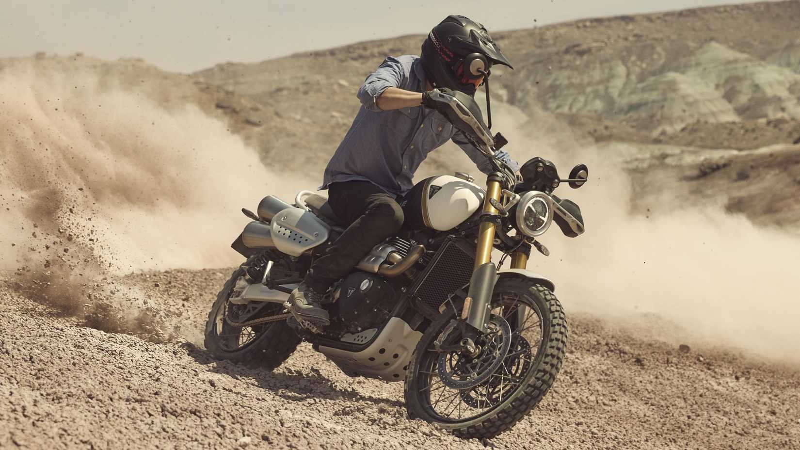 2026 Triumph Bonneville Scrambler 1200 XE sliding on a trail cinematic front third quarter view