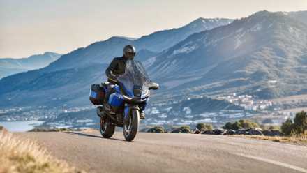 Front shot of the 2026 BMW R 1300 RT driving in front of a mountain range