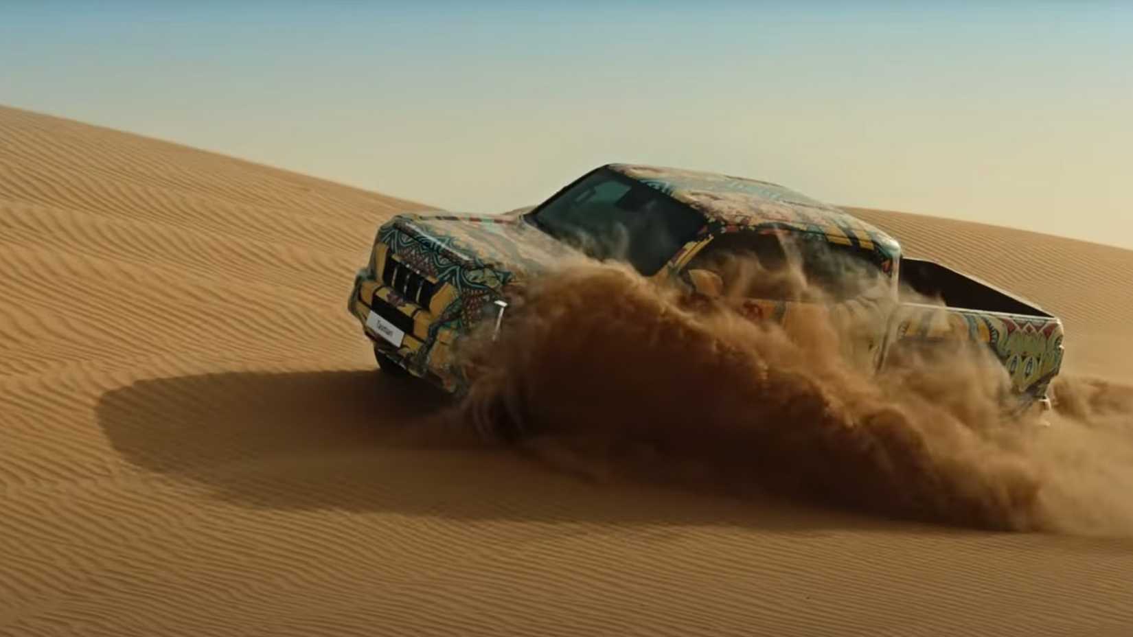 Side shot of a 2025 Kia Tasman thrashing through dunes