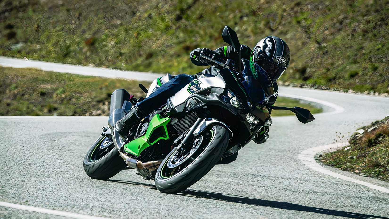 Foto frontal de uma Kawasaki Ninja 7 Hybrid 2024 andando em uma estrada sinuosa