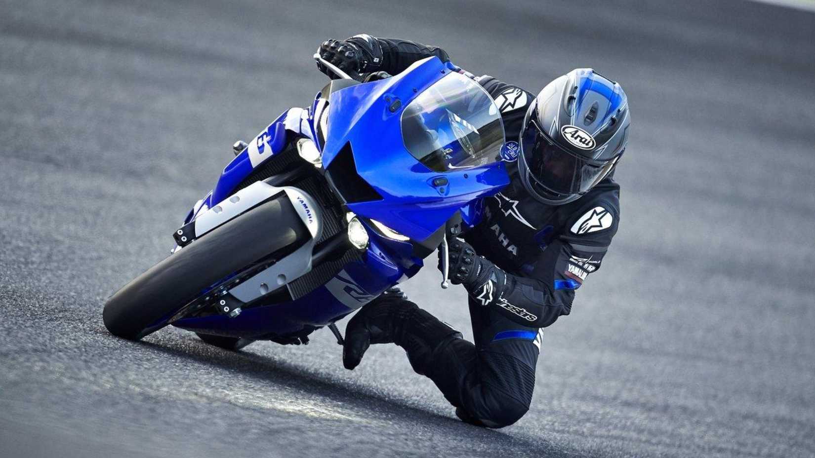 Rider cornering aggressively on a blue Yamaha R6