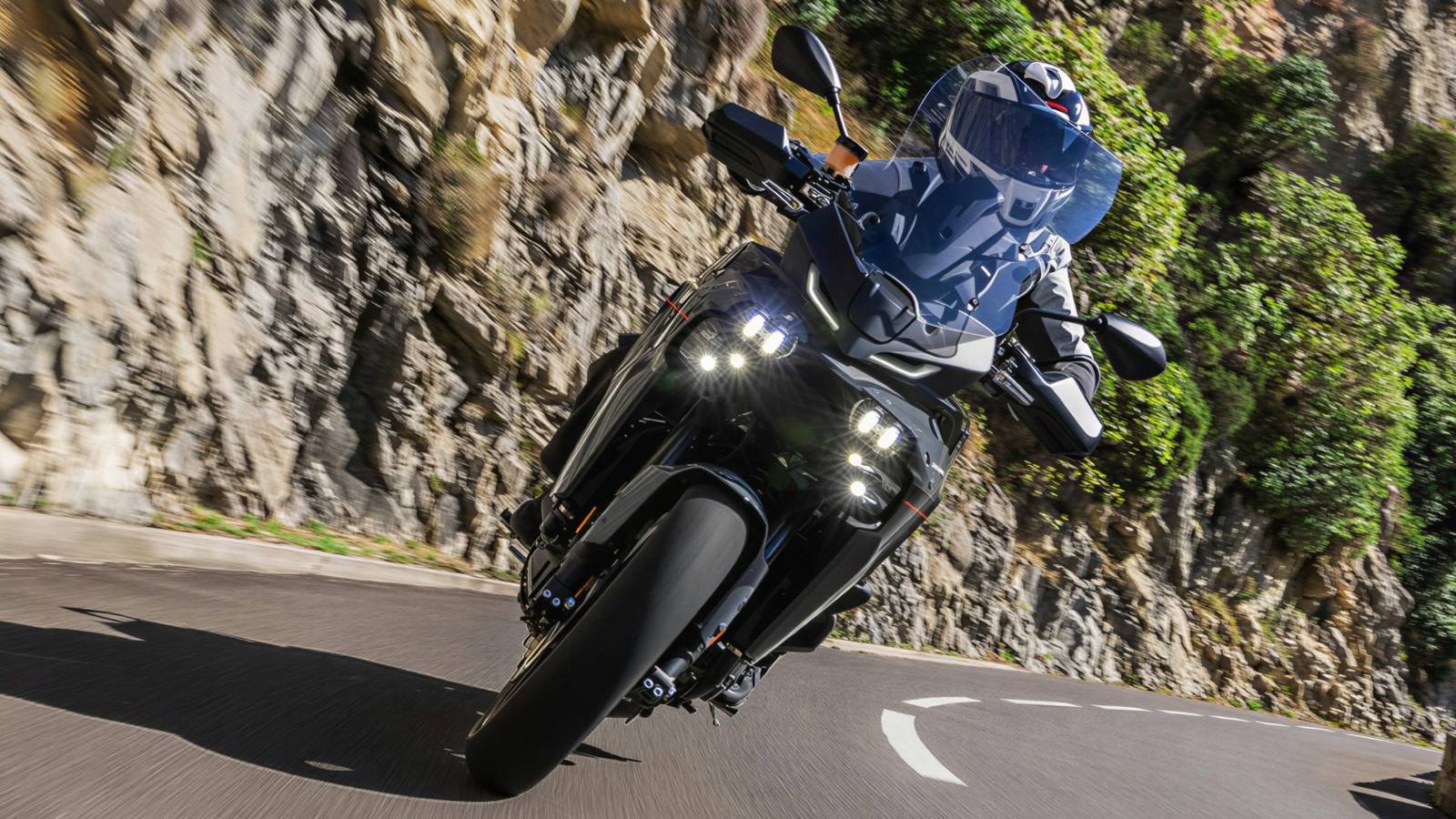 Un rider su una Yamaha Tracer 9 si muove lungo una strada montana con un paesaggio mozzafiato
