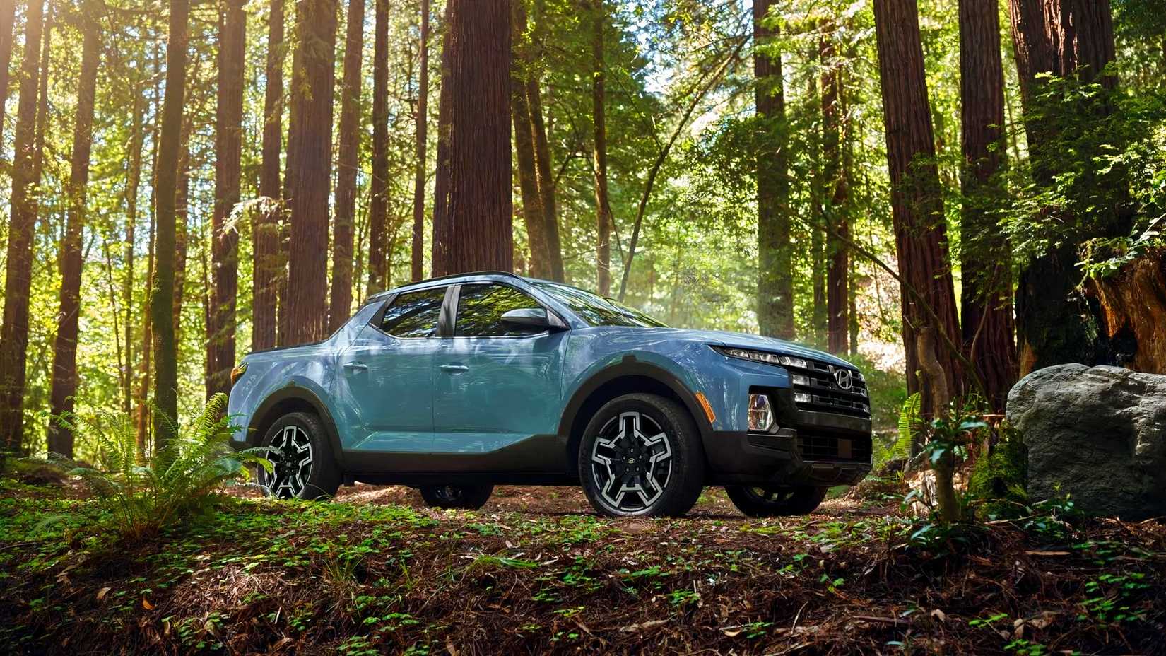 Low-angle front 3/4 shot of 2026 Hyundai Santa Cruz parked in woods