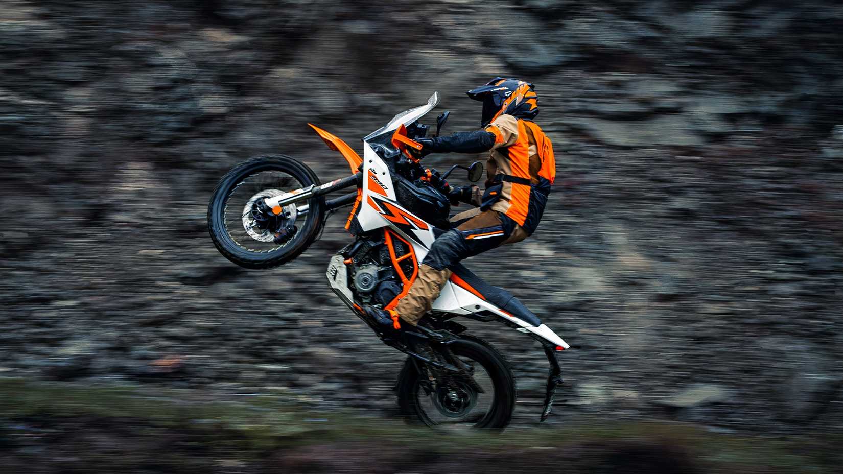 A rider pulling a wheelie off-road aboard the 2026 KTM 390 Adventure