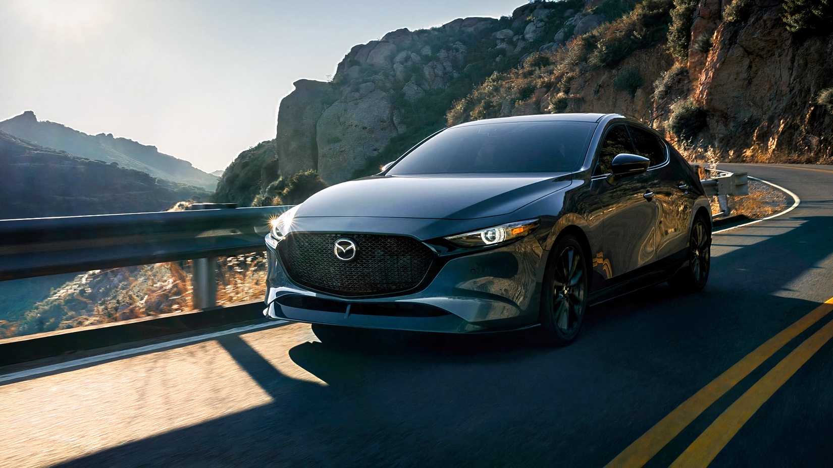 Tiro frontal do Mazda3 hatchback 2026 dirigindo em estrada sinuosa
