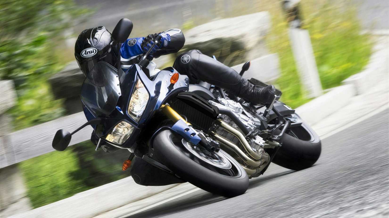 Yamaha Fazer 1000 2015 fazendo curvas ao longo de uma estrada sinuosa, cena cinematográfica frontal do terceiro quarto