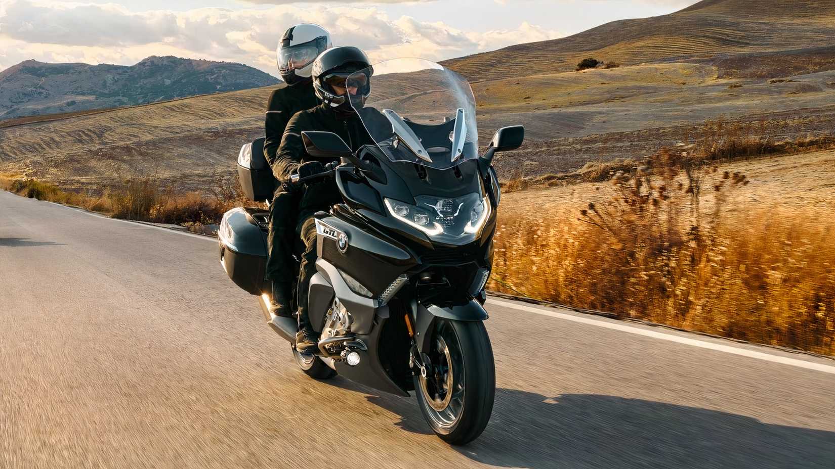 Front shot of a rider and pillion aboard the BMW K 1600 GTL driving down country road