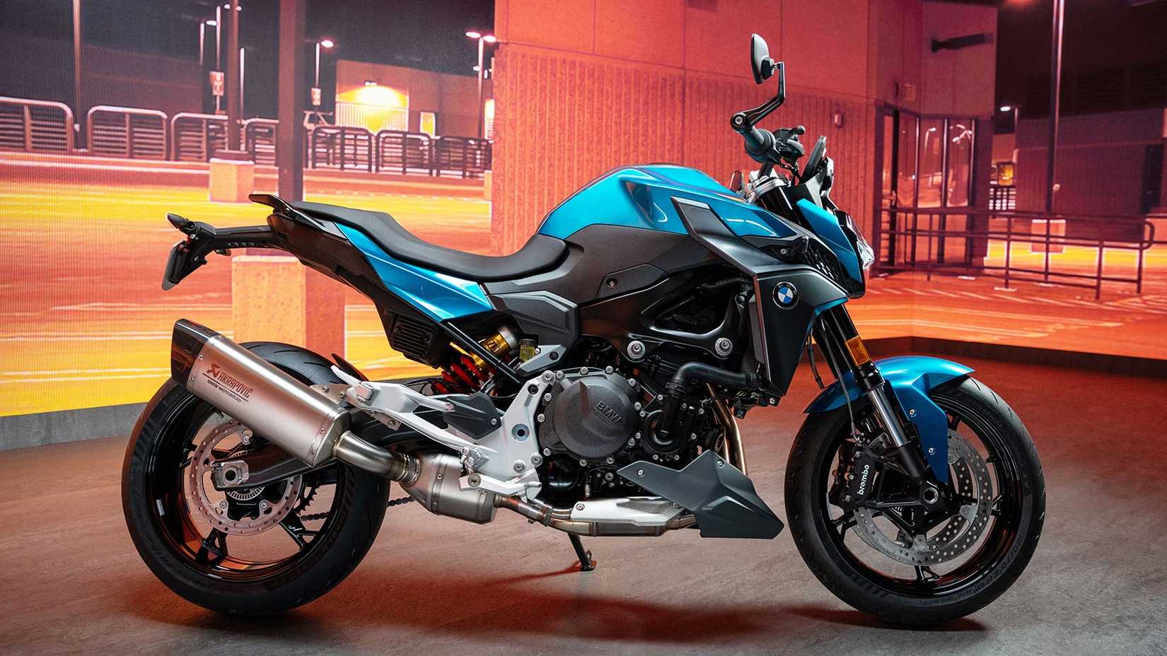 A blue BMW F 900 R parked in a parking lot, side profile view