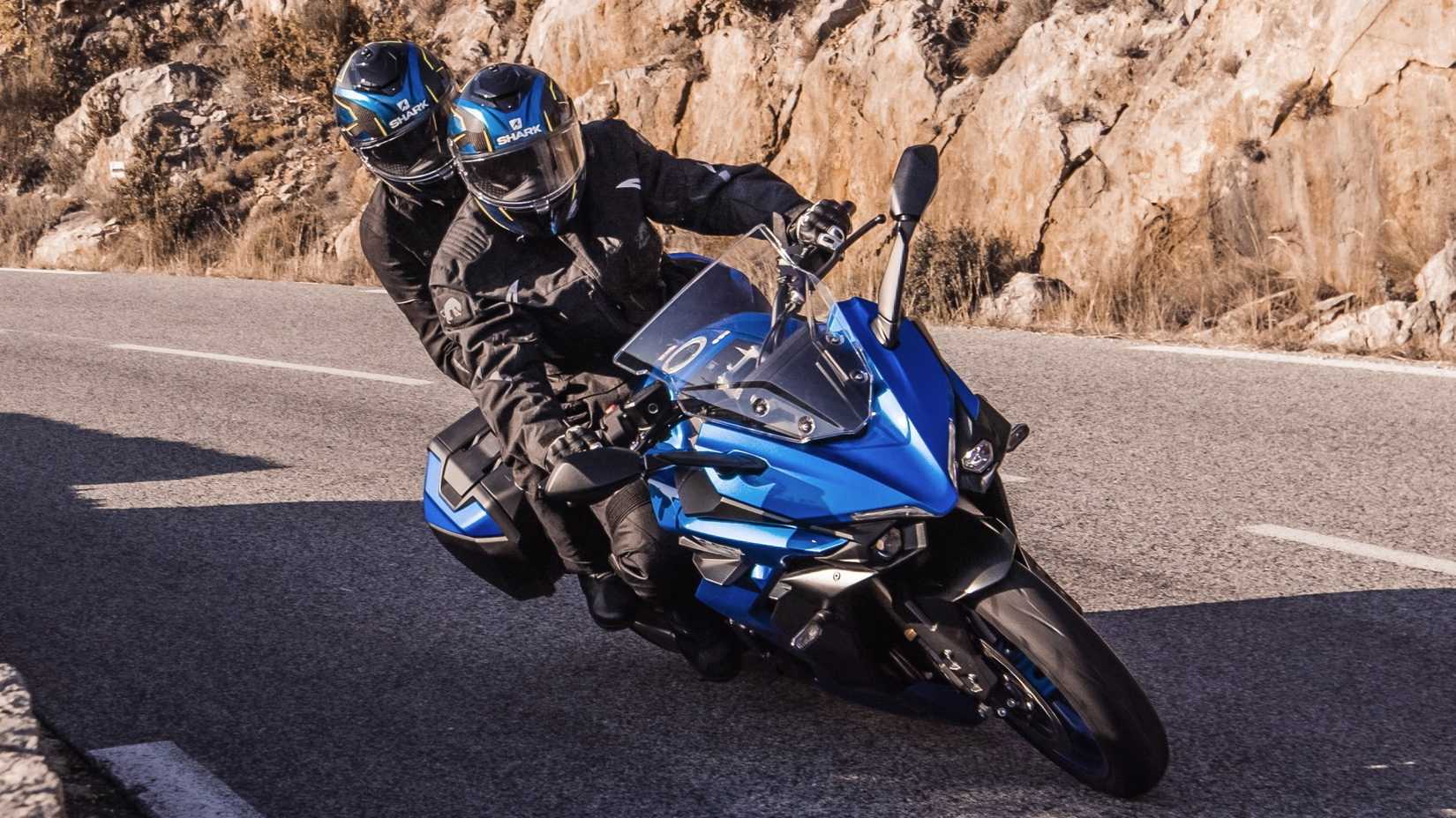 2026 Suzuki GSX-S1000GT + curvando suavemente com um passageiro e caixas laterais na frente do terceiro quarto