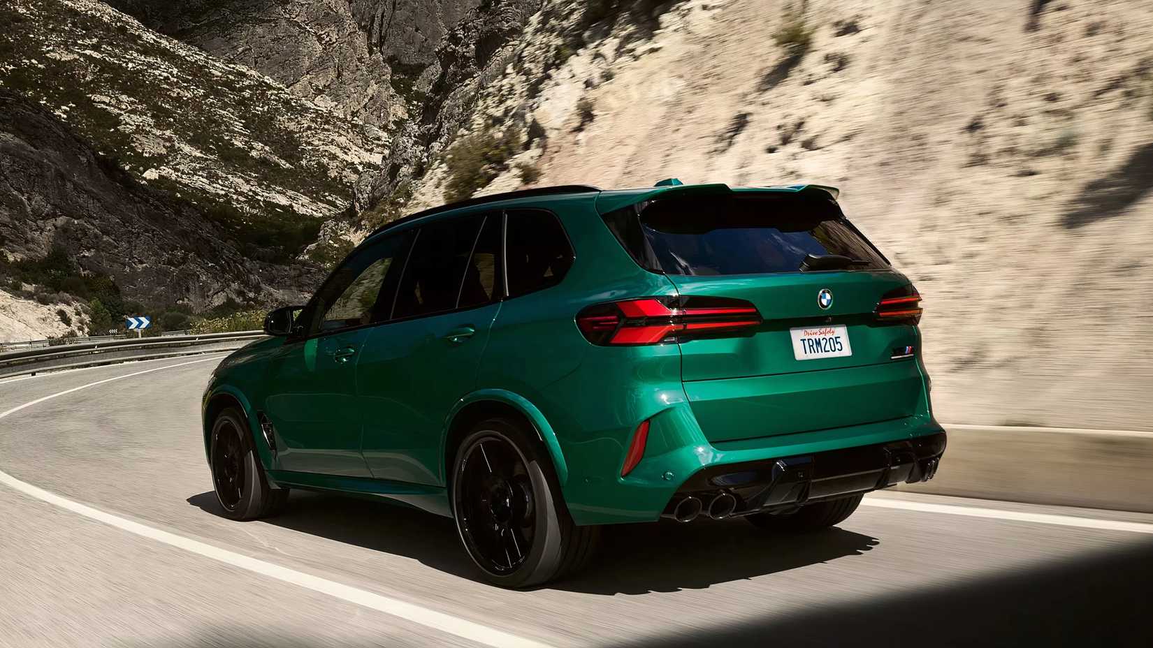 Rear 3/4 action shot of 2026 BMW X5 M driving on road