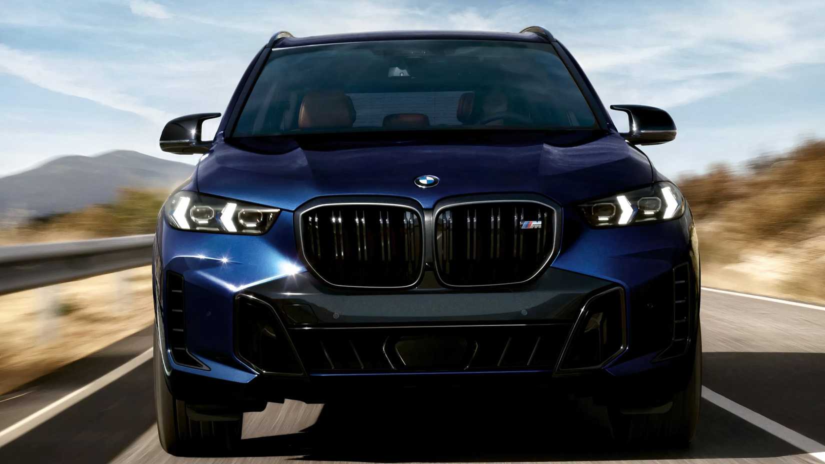 Front action shot of 2026 BMW X5 M driving on road