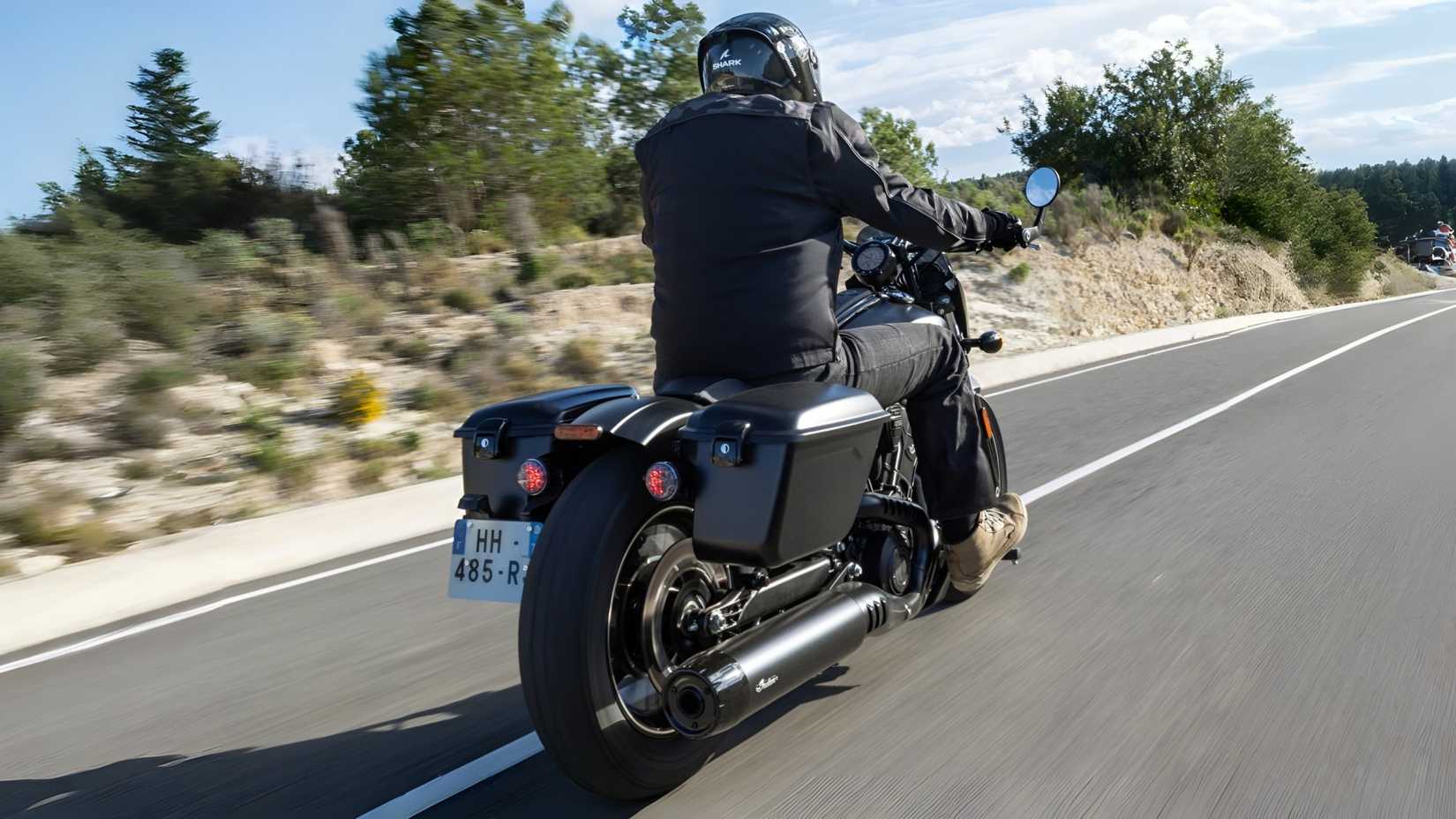 2026 Indian Sport Scout RT em preto cruzando a rodovia, vista traseira do terceiro quarto