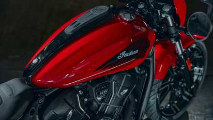 2026 Indian Sport Scout RT em vermelho exibindo seus adesivos legais do tanque de combustível na parte traseira do terceiro quarto, vista do ariel