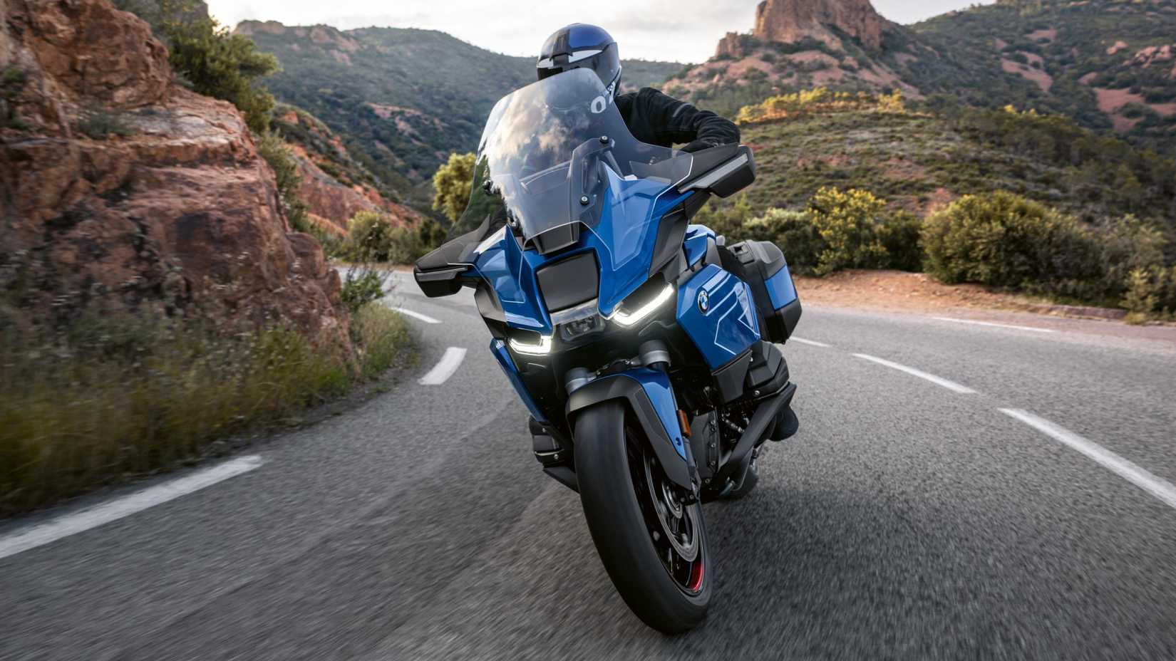 2026 BMW R 1300 RT curvando ao longo de uma estrada em um desfiladeiro, foto cinematográfica do terceiro quarto